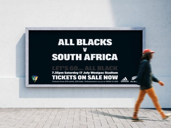 Billboard advertising All Blacks v South Africa rugby match, person walking by.