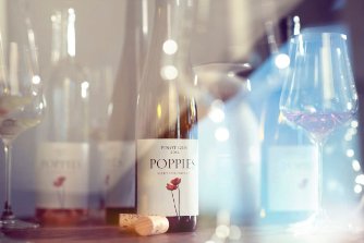 Wine bottle and glasses on wooden table with bokeh lights. Poppies Martinborough Brand Development