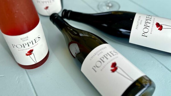 Bottles of Poppies Rosé and Chardonnay wine on table.